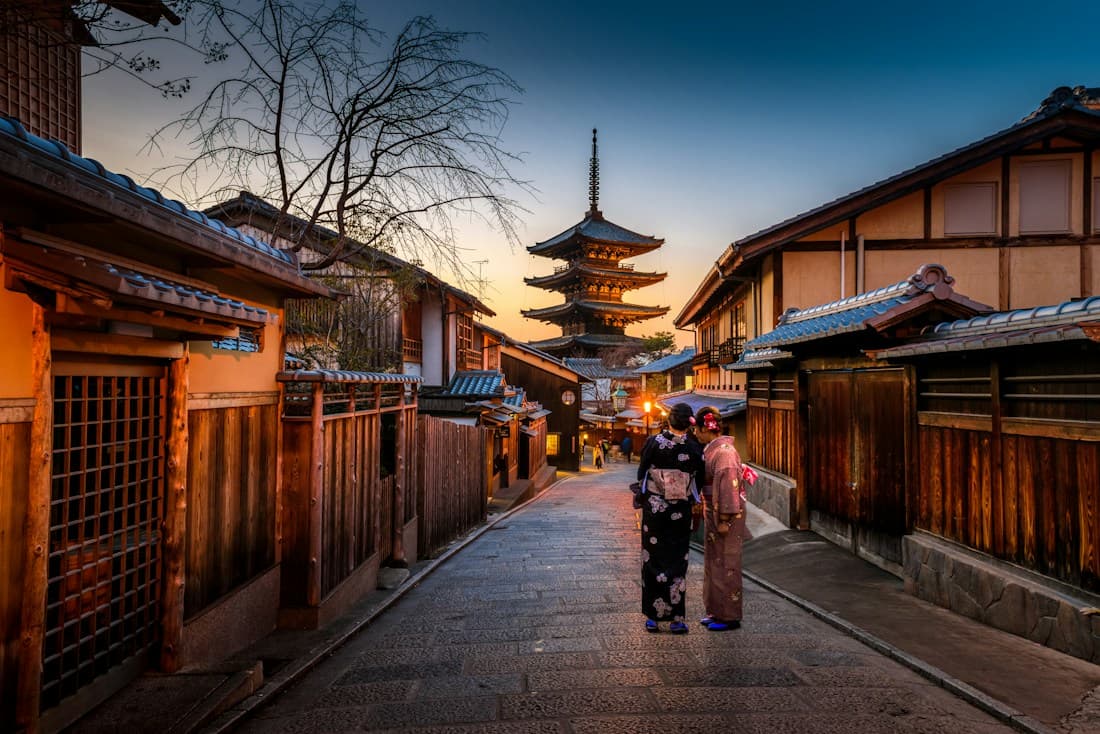 Traditional Japanese architecture framed by trees and a mountain landscape