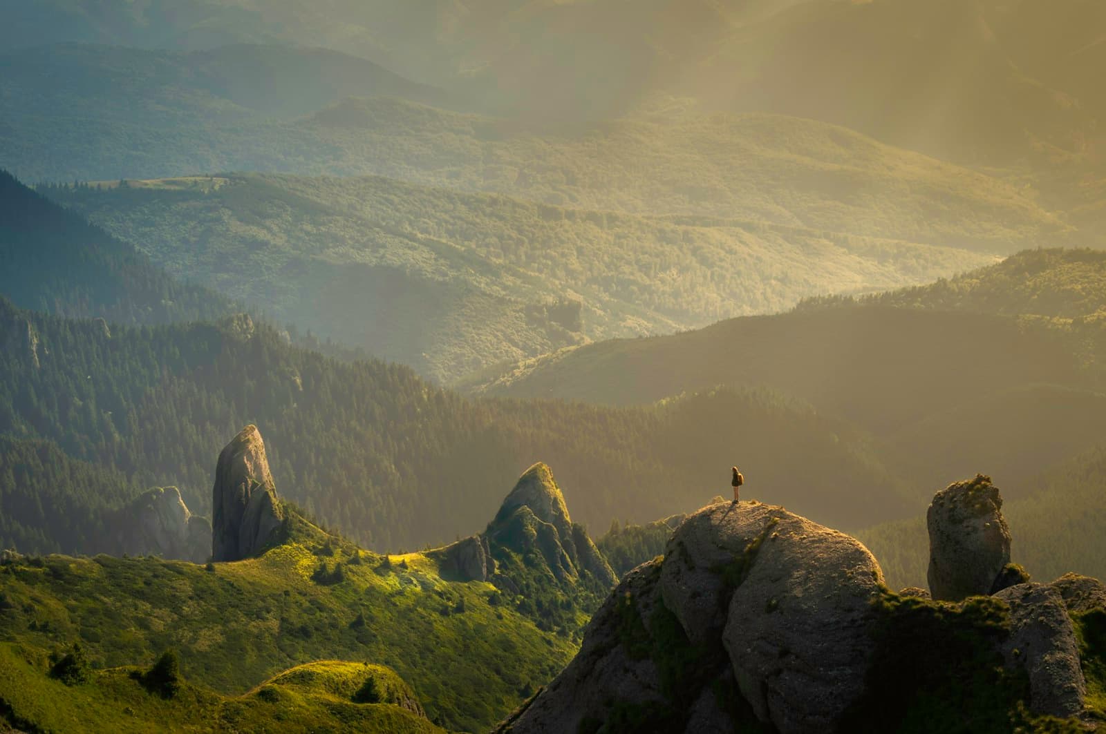 A sunlit mountain valley stretching into the distance beneath a dramatic sky